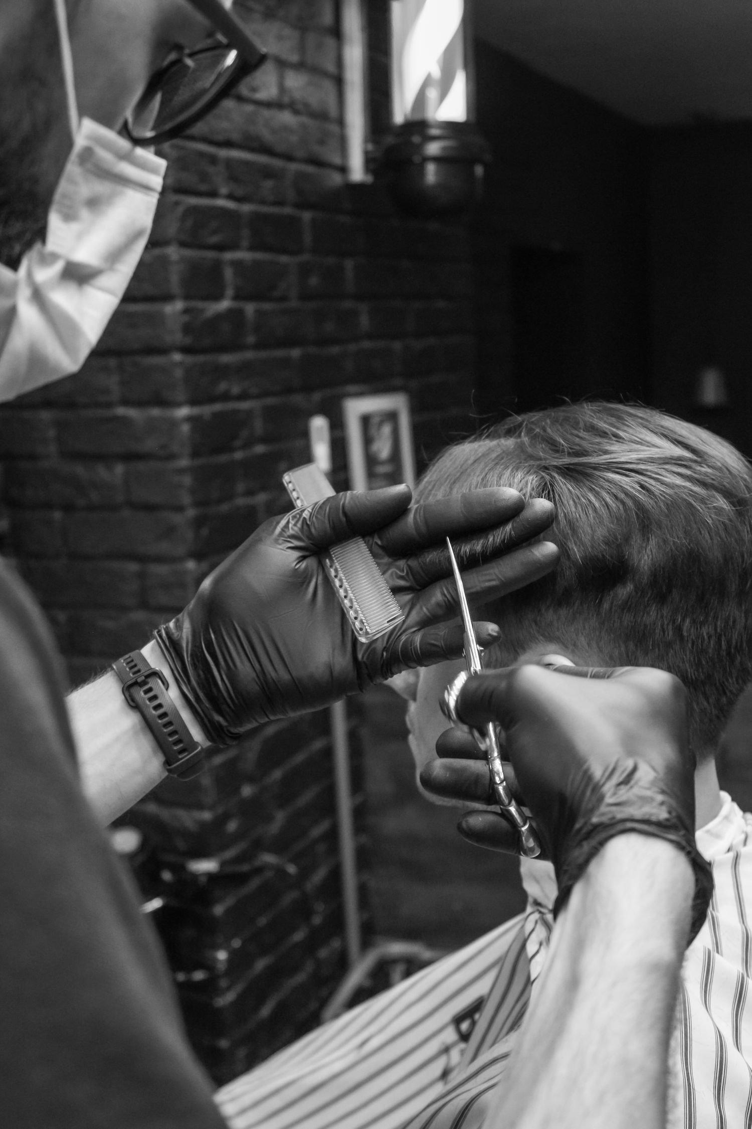 Barbeiro aparando o cabelo com tesoura e pente, em preto e branco